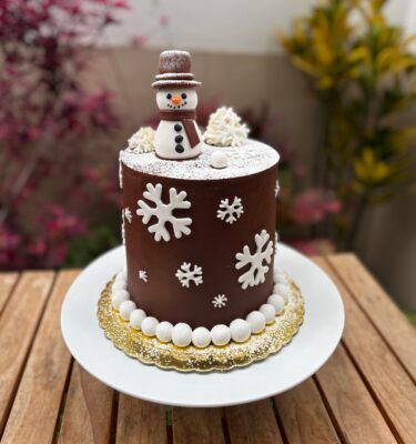 Torta navideña decorada en fondant con diseño de hombre de nieve y detalles invernales.
