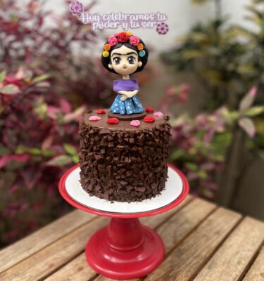 Torta “Trocitos”, una torta de chocolate con trocitos de chocolate, decorada con una muñeca de Frida Kahlo en fondant por el Día de la Mujer.