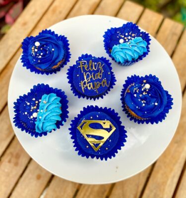 Pack de 6 cupcakes con buttercream, decorados con toppers de cartulina que incluyen la frase "Feliz día papá" y el logo de Superman, ideales para celebrar el Día del Padre.