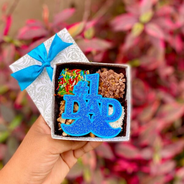 Celebra a papá con nuestros Mini Four #1 Dad, un detalle dulce hecho con fudge de chocolate, toppings irresistibles y un topper especial que dice lo mucho que lo quieres. Perfecto para regalar con cariño en su día.