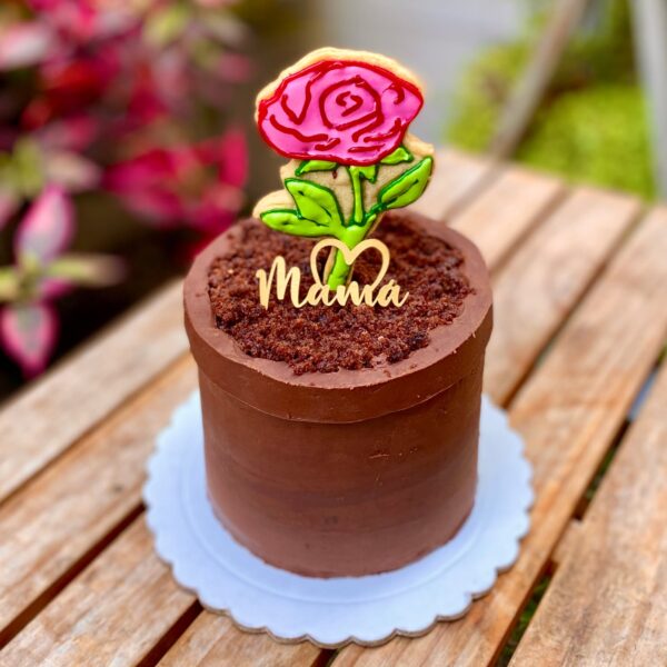Mini torta en forma de maceta con una rosa de galleta en el centro y topper de cartulina que dice “Mamá”.