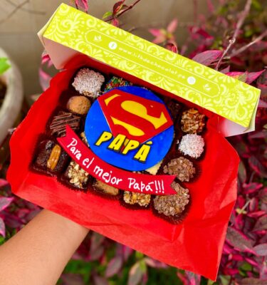 Caja Mix Box con variedad de brownies, trufas y alfajores decorados con fondant del logo de Superman y la palabra “Papá”, acompañados de un cintillo que dice “Para el mejor papá”.