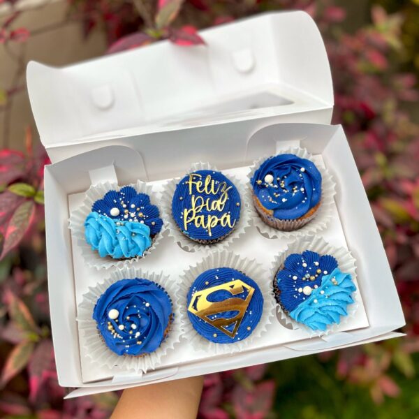 Pack de 6 cupcakes con buttercream, decorados con toppers de cartulina que incluyen la frase "Feliz día papá" y el logo de Superman, ideales para celebrar el Día del Padre.