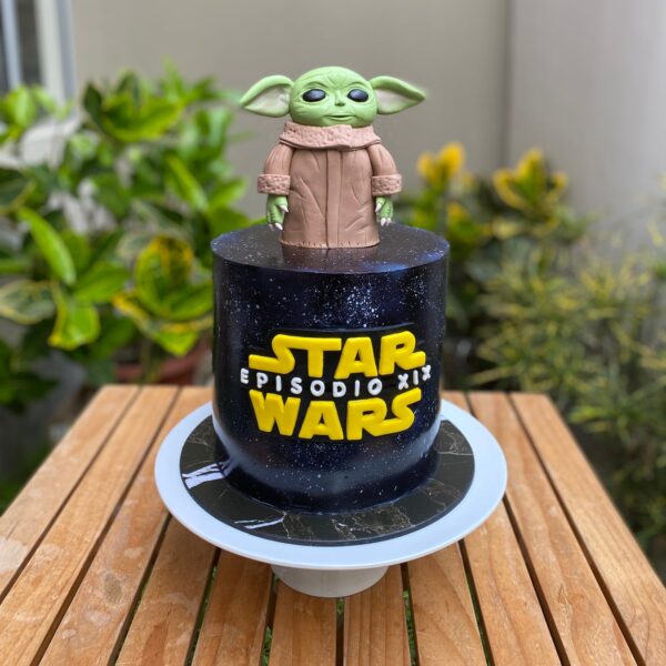 Torta de un piso con Grogu en la parte superior y el logo de Star Wars en el frente, decorada con fondant.