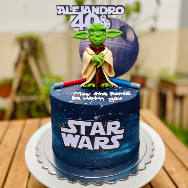 Torta de Star Wars de un piso decorada con fondant, logo de Star Wars, Maestro Yoda en fondant, dos sables de luz y toppers de cartulina.