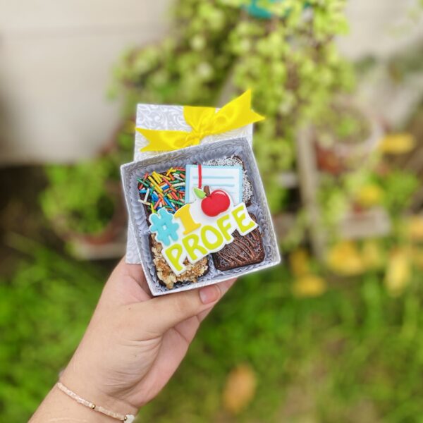 Un detalle dulce para quienes nos enseñan con el corazón. Nuestro mini four de brownies por el Día del Maestro viene con decoraciones en fondant: una manzanita, un cuaderno y el clásico #1 profe