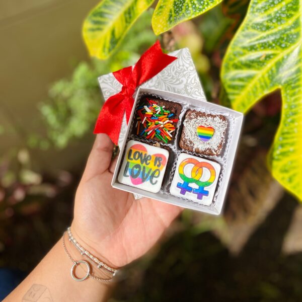 Mini Four de brownies decorados con fondant: uno con la frase “Love is Love”, otro con un corazón en colores Pride y otro con símbolos de mujer entrelazados con los colores del arcoíris.