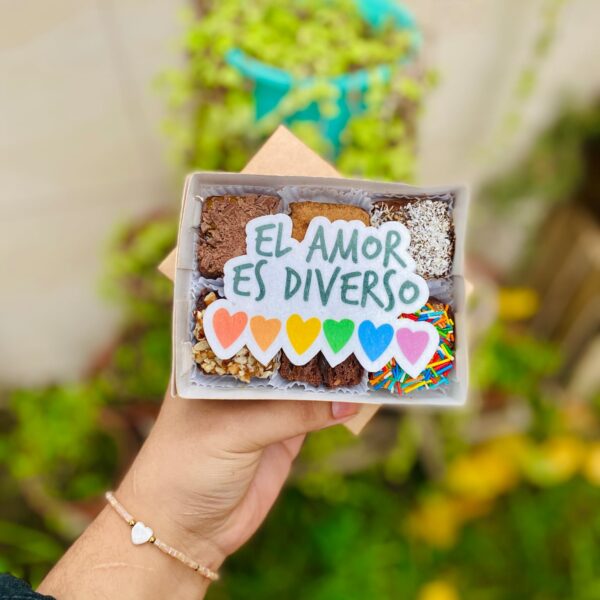 Caja con 6 brownies decorados con un topper de papel de arroz que dice “El amor es diverso” y corazones con los colores de la bandera del Pride.
