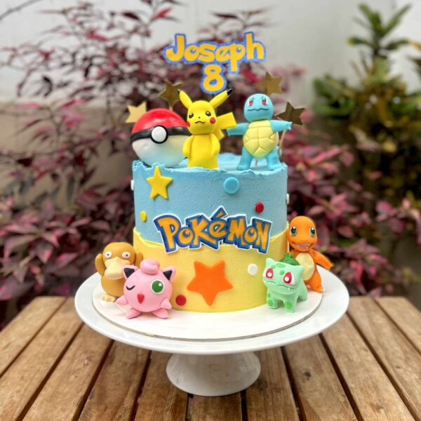 Torta temática de Pokémon decorada con buttercream en tonos celeste y amarillo. Incluye seis figuras de Pokémon y una Pokebola modeladas en fondant.