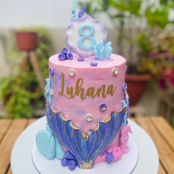 Torta de sirena de un piso, decorada con buttercream y detalles de fondant como conchitas, algas y una ola de sirena en el centro.
