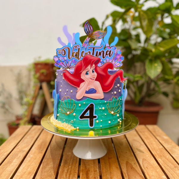 Torta de un piso inspirada en La Sirenita, bañada en buttercream y decorada con toppers de cartulina del personaje y elementos marinos.