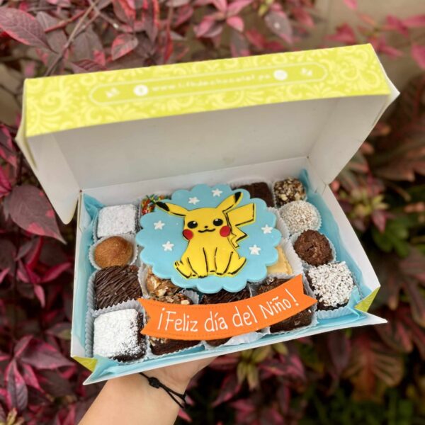 Caja Mix Box con trufas, brownies y alfajores decorados con un Pikachu de fondant y un banner que dice "Feliz Día del Niño"