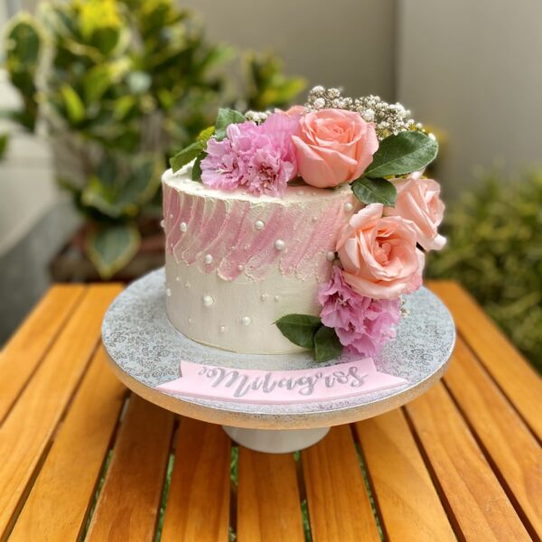 Torta de un piso bañada en buttercream, decorada con flores naturales en tonos delicados.