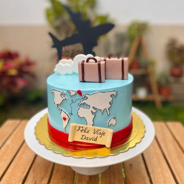 Torta viajera decorada con fondant, mapa del mundo, maletas, nubes y topper de avión, ideal para amantes de los viajes.