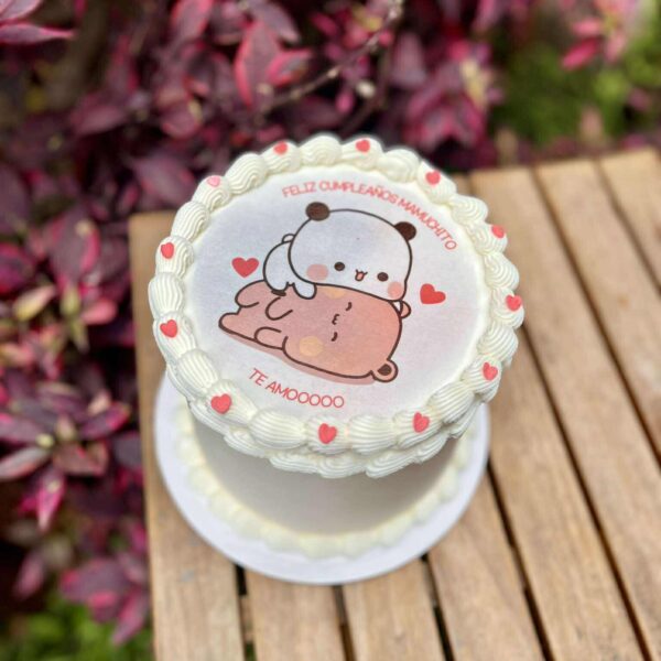 Burncake bañado en buttercream blanco, decorado con delicados rosetones, pequeños corazones de fondant y una imagen central tierna de los ositos Dudu y Bubu
