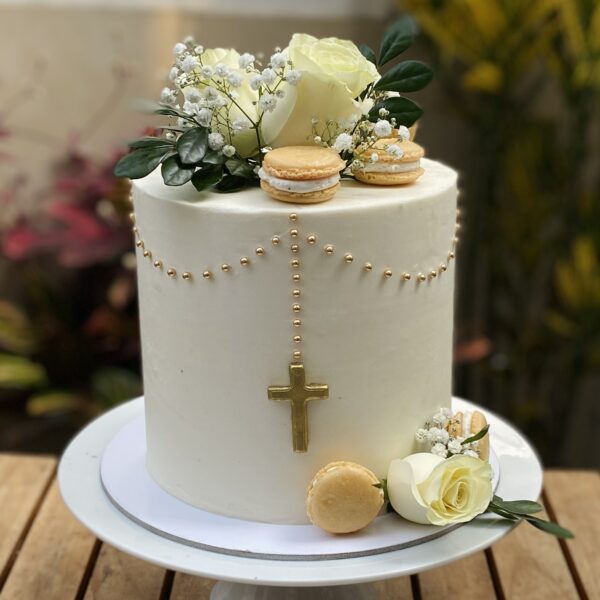 Torta de un piso para Primera Comunión, decorada con macarons franceses, flores naturales, perlas comestibles y una cruz de fondant al centro.