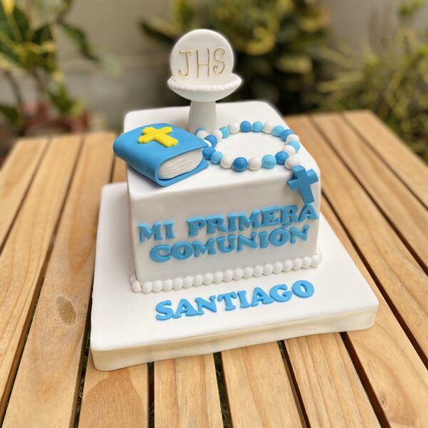 Torta de Primera Comunión de un piso, forrada en fondant blanco y decorada con cáliz, libro y rosario en fondant, más la frase “Mi Primera Comunión”.