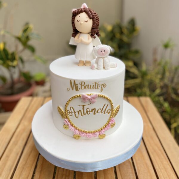 Torta de bautizo en fondant, con niña en 3D de azúcar, ovejita, marco floral y topper dorado.