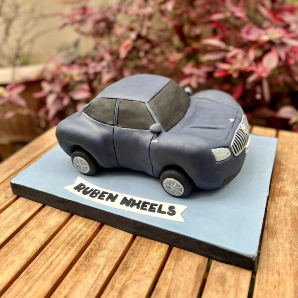 Torta tallada en forma de auto, acabada en fondant y pre bañada en ganache de chocolate, con personalización de nombre.