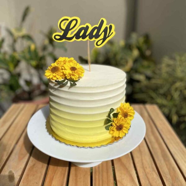 Torta de un piso bañada en buttercream blanco y amarillo, decorada con flores naturales amarillas en la parte superior y los laterales.