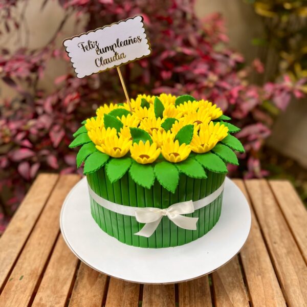 Torta de fondant en forma de ramo de girasoles, decorada en verde y con girasoles de fondant en la parte superior.