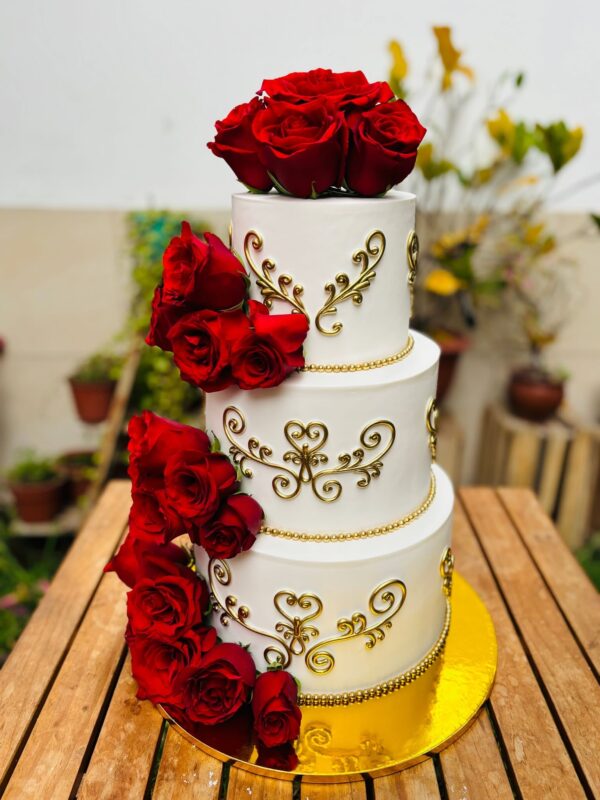 Pastel de quinceañero de tres pisos, decorado con rosas rojas naturales y detalles en fondant dorado, elegante y sofisticado.