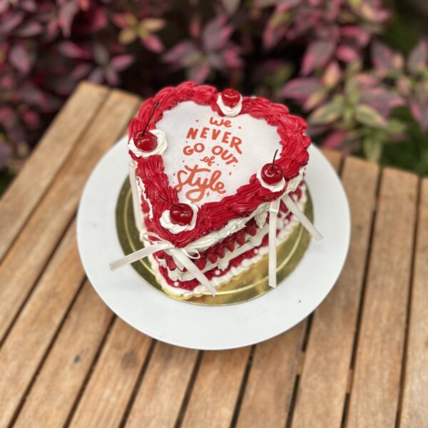 Burncake bañado en buttercream, decorado con perlitas, lazos de tela y cerezas en la parte superior.