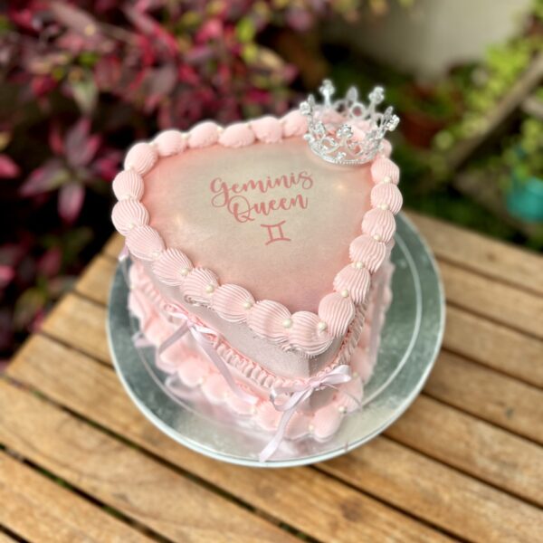 Burncake bañado en buttercream, decorado con lazos de tela a los lados, una pequeña corona de bisutería en la parte superior y perlitas brillantes.