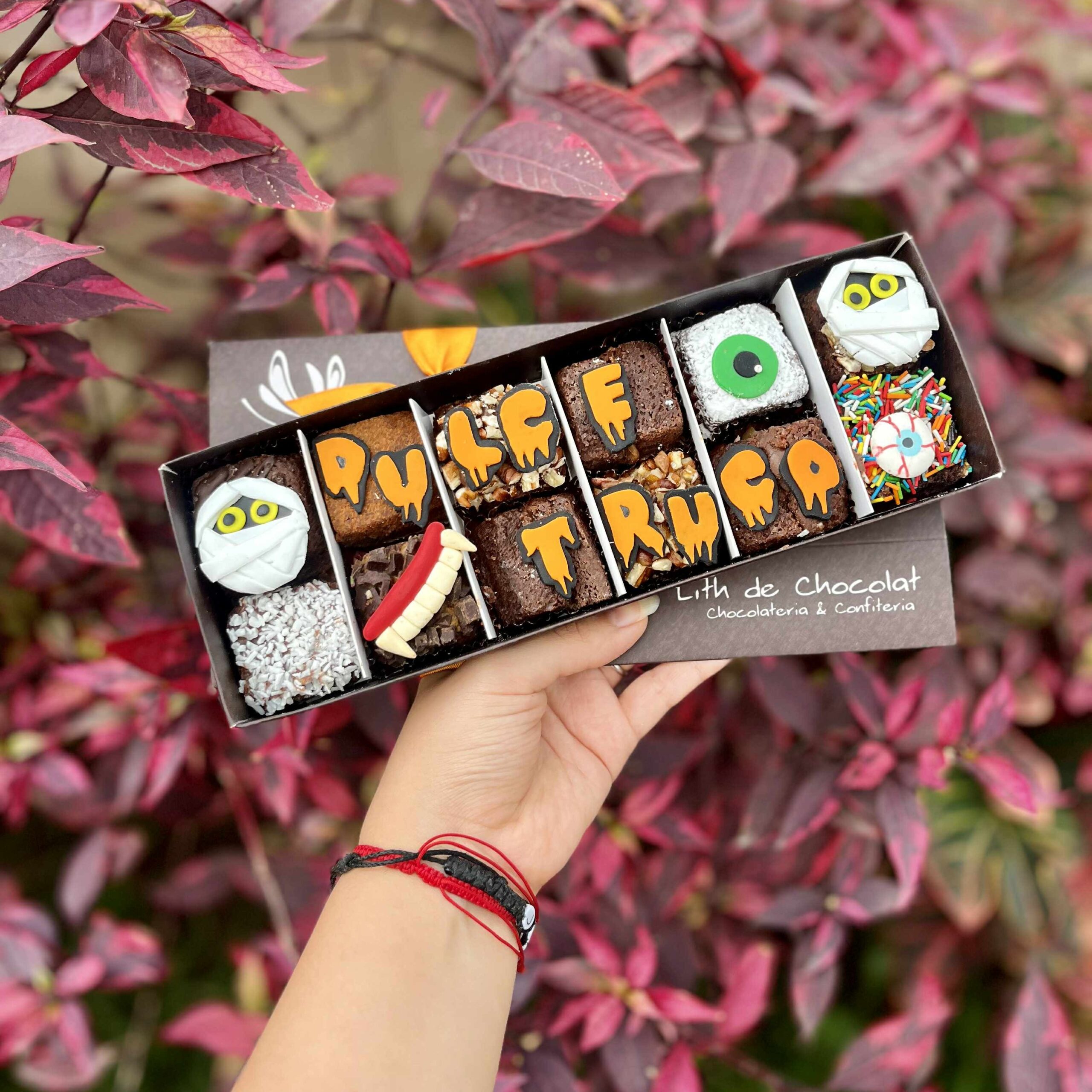 3b749b9d-3cf2-4372-8918-fb839d94b59f Caja de brownies decorados con temática de Halloween, con detalles en fondant de momias, ojos, dientes de vampiro y la frase “Dulce o truco”.