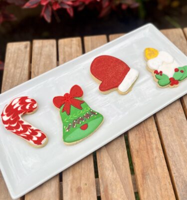 Pack de 6 galletas decoradas con glaseado navideño en diferentes diseños: campana, corona, guante, gorro, vela, bota, árbol, Santa Claus o muñeco de nieve.