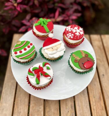 Pack de 6 cupcakes decorados en fondant con figuras navideñas: Santa, Rodolfo el reno, una esfera, dos bastones, un regalo y copos de nieve.