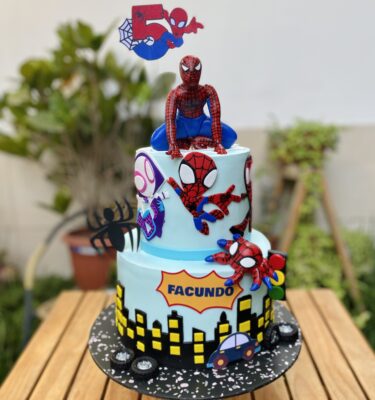 Torta de dos pisos decorada en fondant, con detalles en 2D y figura 3D de Spiderman en la parte superior.