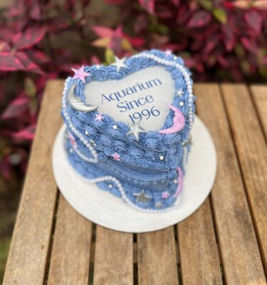 Burncake del signo Acuario decorado en buttercream, con estrellas y medias lunas en fondant y un delicado collar de perlas alrededor.