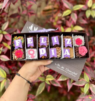 Caja vintage con 12 brownies decorada con piezas de fondant que dicen “Feliz Día”, flores y el símbolo de la mujer, especial por el Día de la Mujer